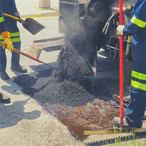 A team of people patching a pothole on a street.